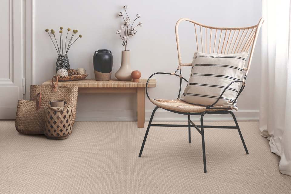 beige looped carpet in living room with natural materials and rattan furniture